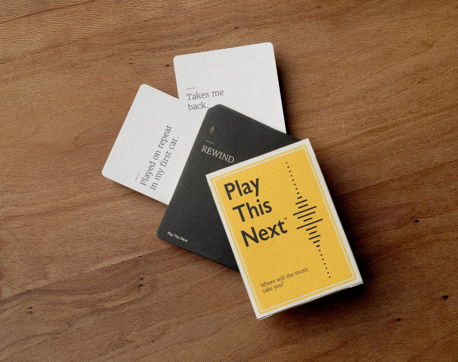 Play This Next card game box with question cards on a wood table